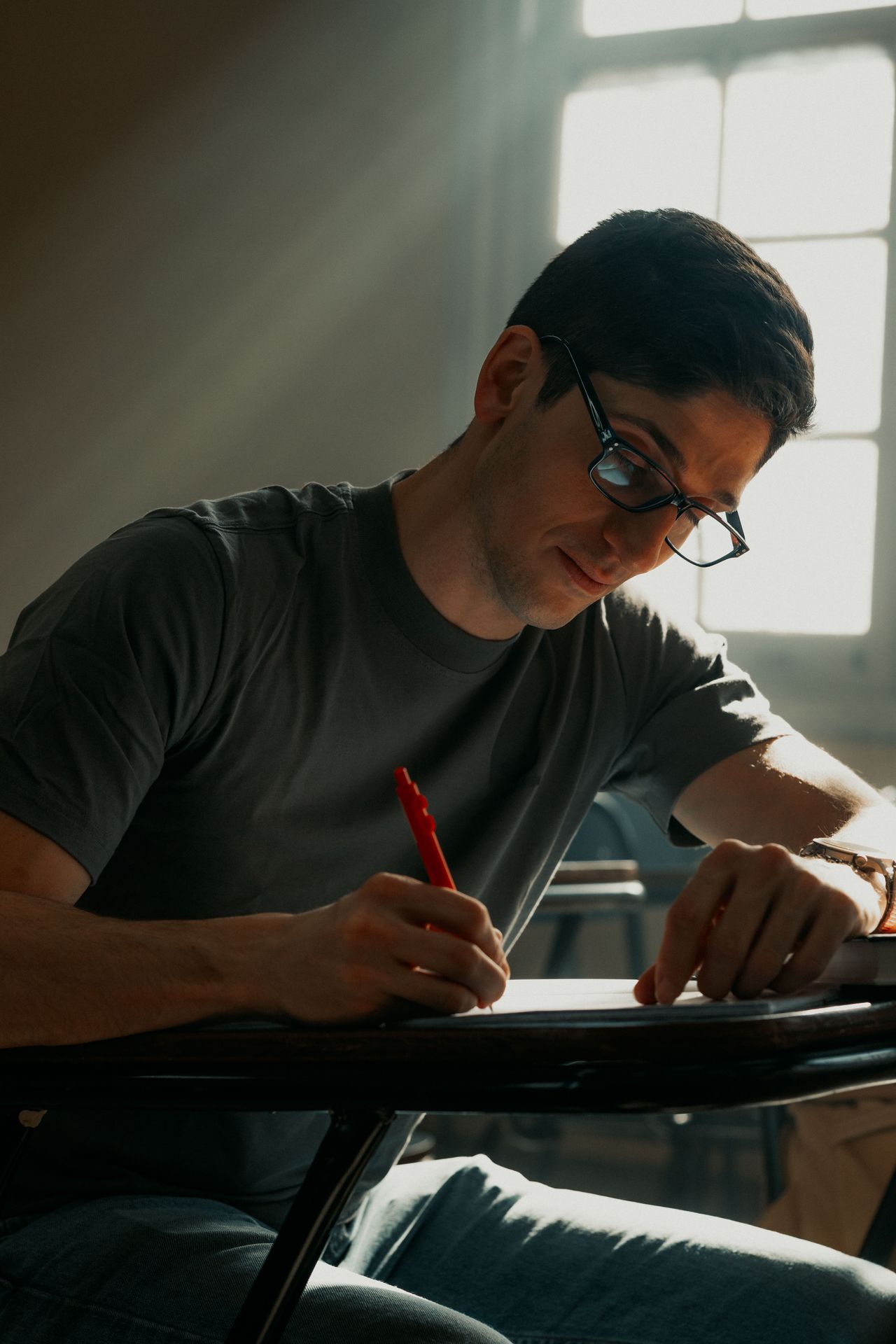 Student studying in a classroom with notes and textbook for IC&RC ADC exam review, CASAC exam prep, and addiction counselor certification.
